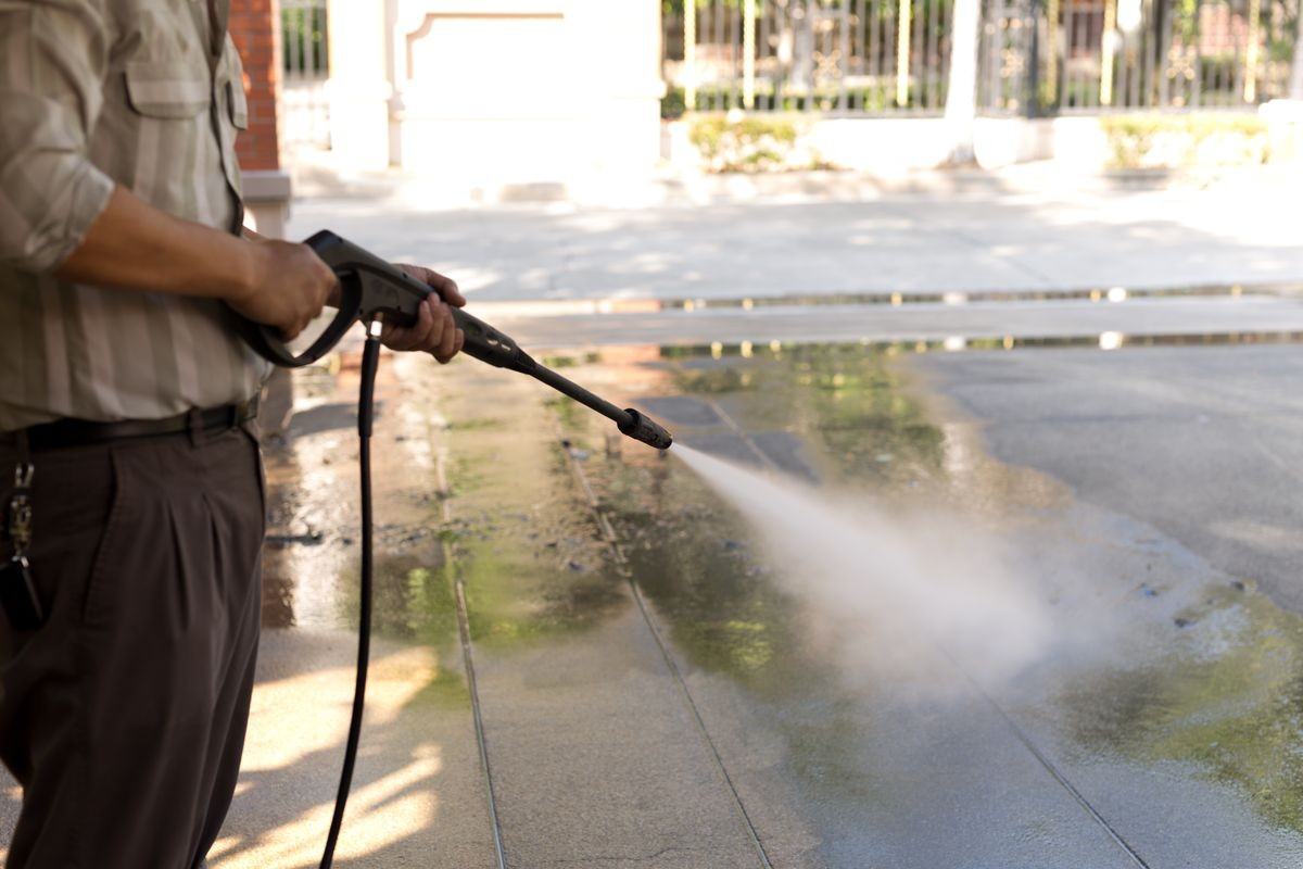 Man cleaning driveway with high pressure water jet at home